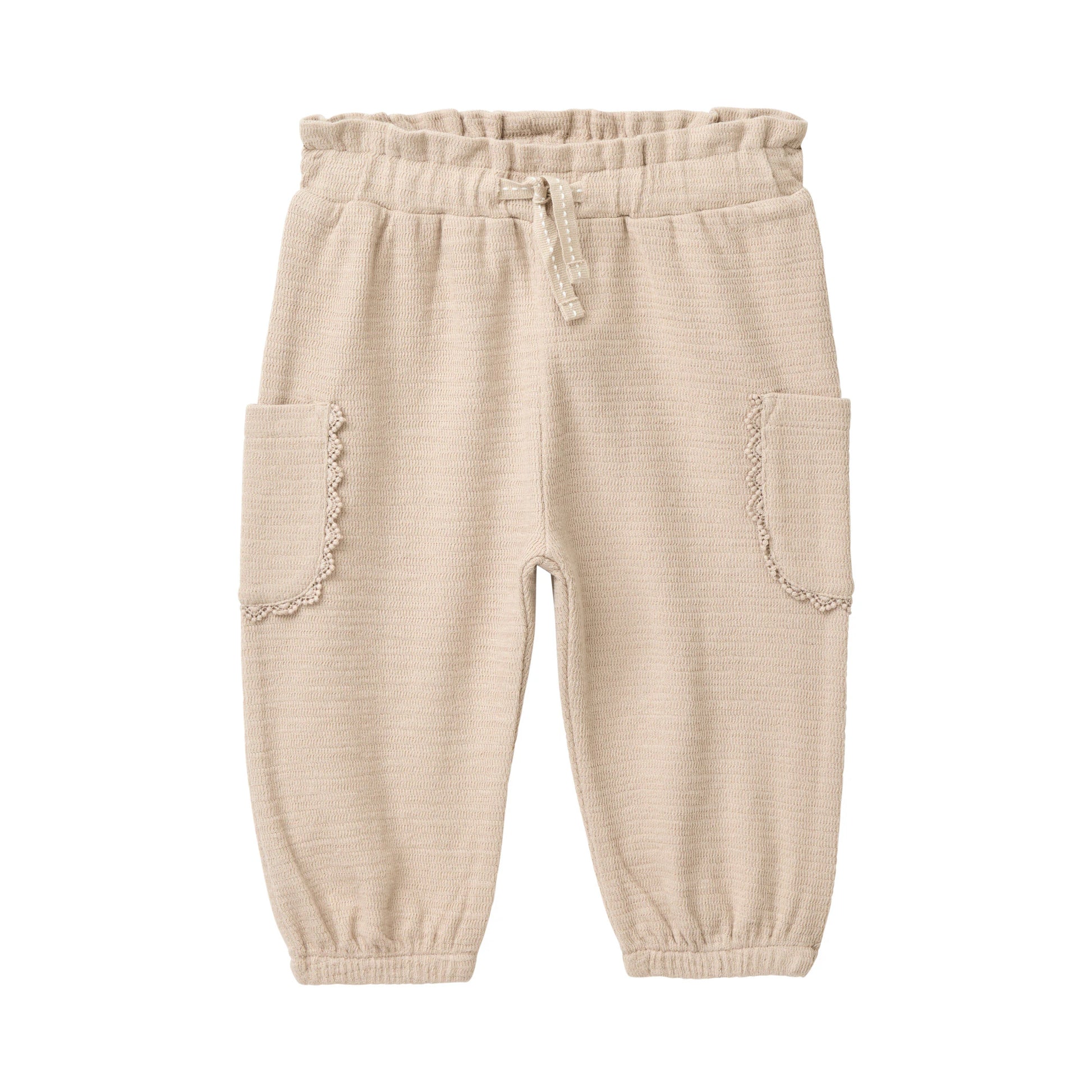Sandfärgade mjukisbyxor för baby i ekologisk bomull med spetskant runt fickorna, från People Wear Organic